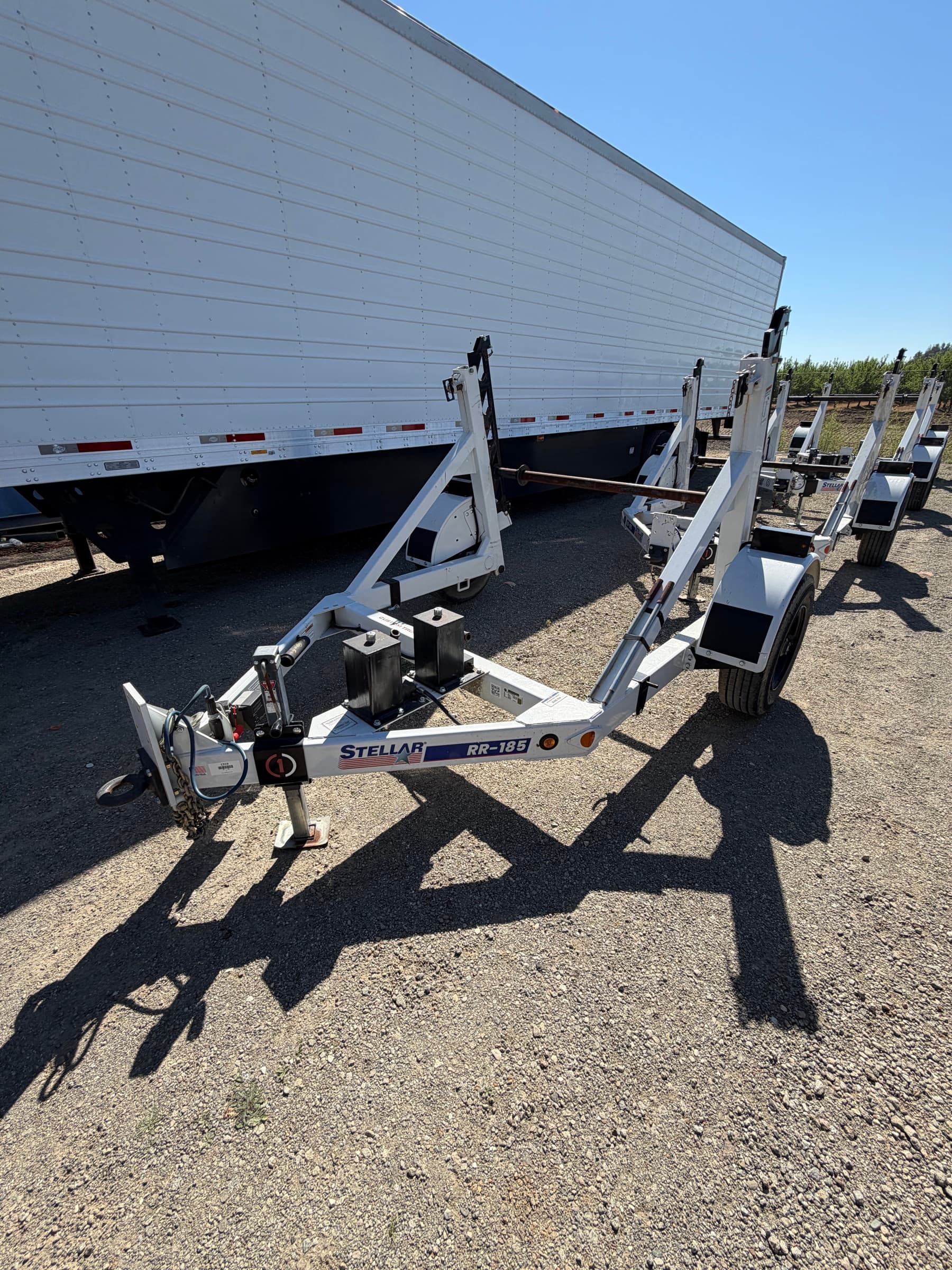 Stellar RR-185 reel trailer alongside a row of matching units and a dry van trailer, RR-185 decal visible on the frame